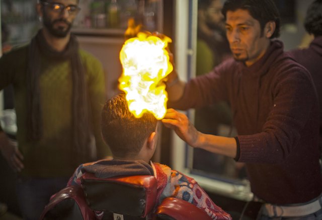 Палестинский парикмахер укладывает волосы клиентов огнём