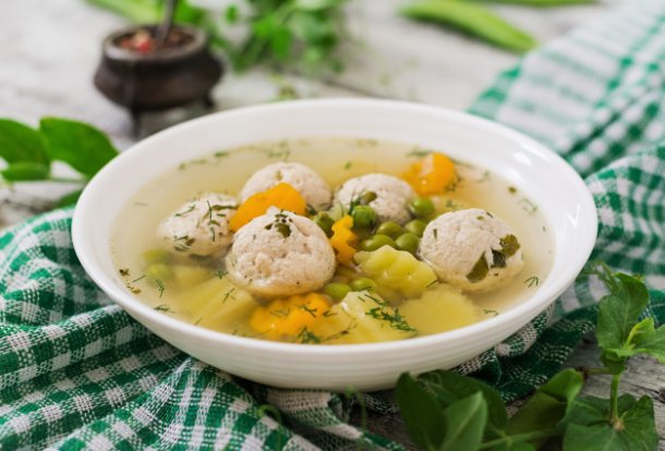 dietary-soup-with-chicken-meatballs-and-green-peas-in-a-white-bowl-on-a-wooden-background_2829-362