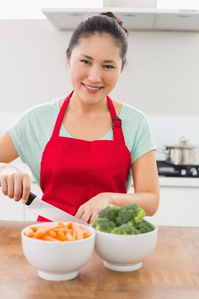 smiling-young-woman-chopping-vegetables-in-kitchen_13339-227010