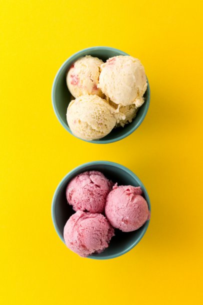 tasty-ice-cream-vanilla-strawberry-scoops-in-blue-bowls-on-yellow-vibrant-background_1220-1824
